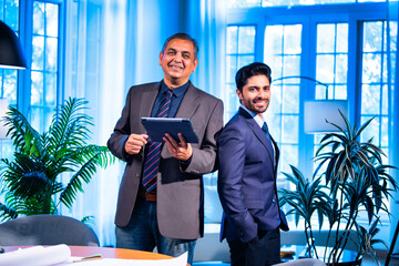 Indian businessmen collaborating on tablet for project planning in professional office space