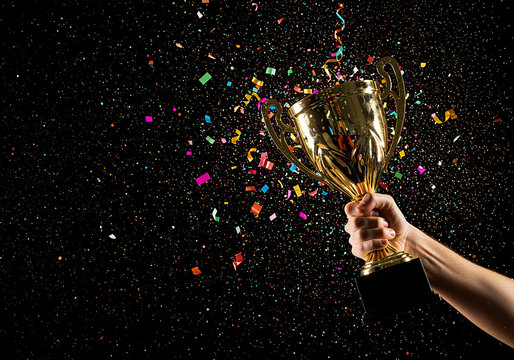 Celebrating a major achievement with a golden winner's trophy held high as vibrant confetti falls against a black background.