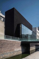 Modern architectural design showcased in a striking black building with glass elements along the waterway in a bustling urban setting, under a clear blue sky