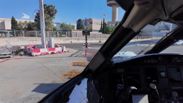 An immersive cockpit view of a push-back maneuver as seen by the pilot, in a sunnyn day with a blue sky.