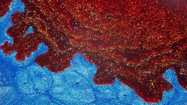 Macro view of iridescent blue ink reacting as red ink is added, creating fluid movement and dynamic displacement across the shimmering surface.