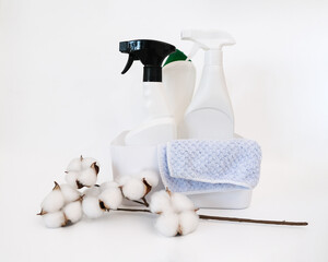 White plastic container with bottles with cleaning products, rag  and cotton branch on white...