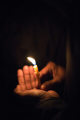 A person is carefully holding a lit lighter in their hand,