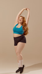 Smiling woman in activewear stretching against neutral backdrop. Concept of graceful movement,...