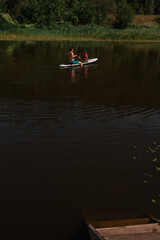 Dad rides his little son on a SUP board on the river in the middle of the forest, summer active...