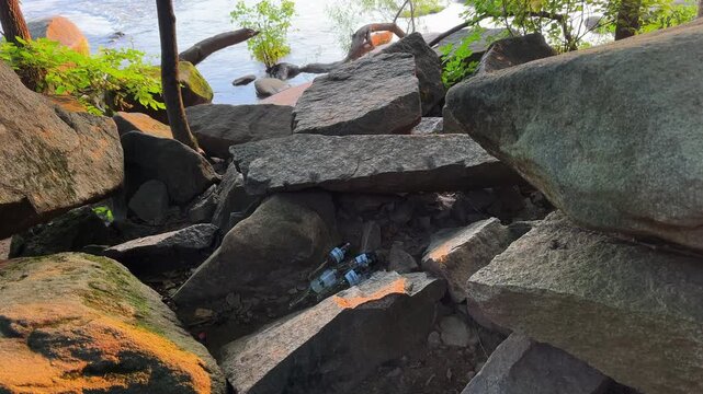 A pile of beer bottles nestled in the rocks at Pony Pasture, James River in Richmond Virginia
