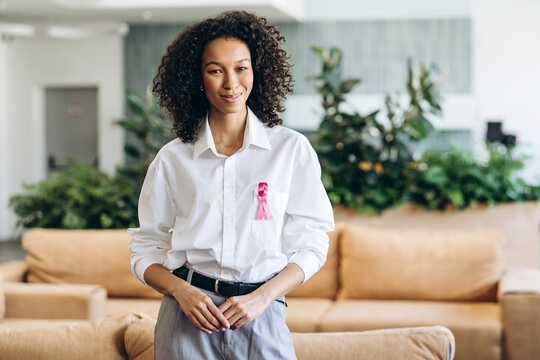 Businesswoman wearing pink ribbon showing support for breast cancer awareness month