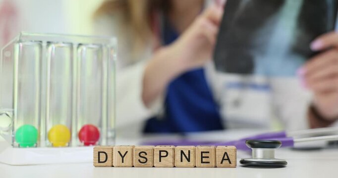 Professional examines X-ray near Dyspnea on wooden blocks and spirometer with colored balls. Breathing difficulties and lung function assessment