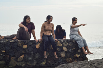The four girls sit in a calm circle on the beach, embracing the quietness of morning as they gaze out at the waves and tropical surroundings.