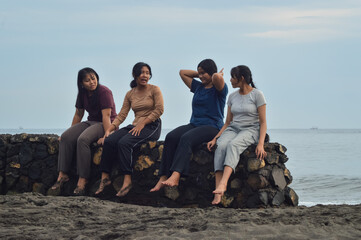 With the soft morning light above them, the girls relax and talk on the sandy shore, soaking in the peaceful coastal moment together.