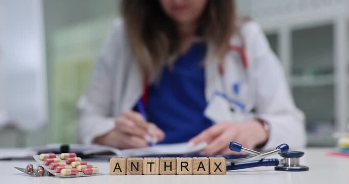 Professional medic actively engaged with paperwork by Anthrax on cubes. Stethoscope and blister pack of pills suggest treatment of infectious disease