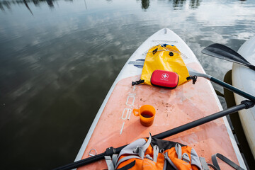 A paddle board that has a bright red first aid kit securely placed on it is currently floating in...