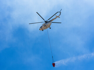 A firefighting helicopter carrying water to a forest fire