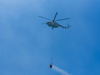 A firefighting helicopter carrying water to a forest fire