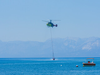 A firefighting helicopter carrying water to a forest fire