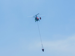 A firefighting helicopter carrying water to a forest fire