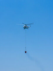 A firefighting helicopter carrying water to a forest fire