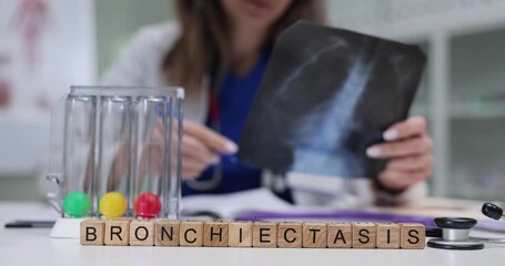 Wooden cubes show Bronchiectasis standing by X-ray image and breath test tubes. Woman pulmonologist checks lung picture controlling breathing problem