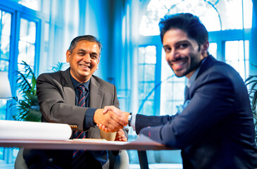 Young Indian professionals seal business deal with handshake in modern office setting