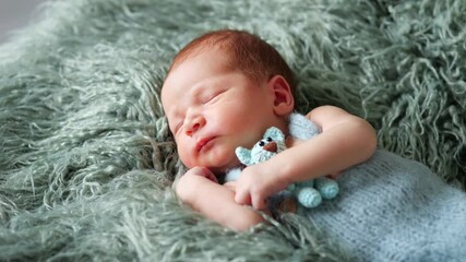 Sleeping baby boy in blue outfit gently clutches teddy bear