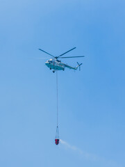 A firefighting helicopter carrying water to a forest fire