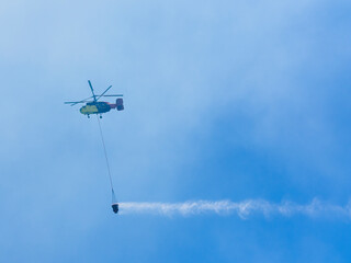 A firefighting helicopter carrying water to a forest fire