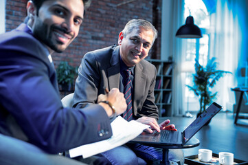 Indian business professionals using laptop at office desk for teamwork and project collaboration