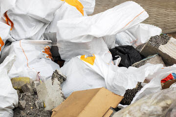 A pile of trash includes a black bag and a white bag