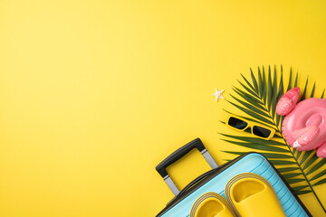 Vacation essentials on yellow background featuring suitcase, sandals, sunglasses, tropical leaves,...
