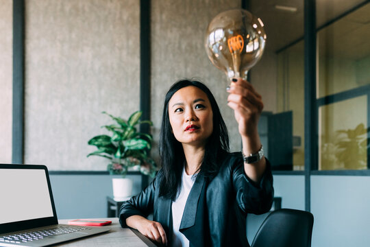 Businesswoman analyzing light bulb at office