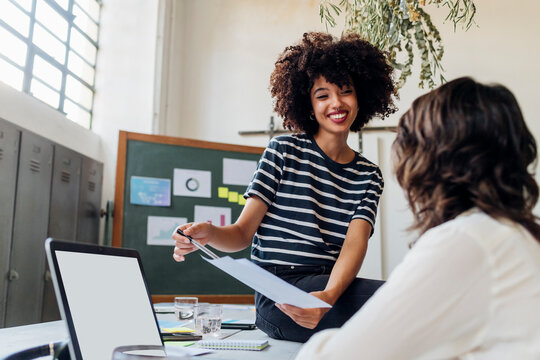 Smiling businesswoman explaining report to colleague at office