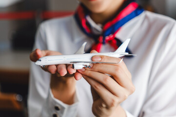Close-up of airline staff holding model airplane in hands. Concept of aviation service, flight planning, airline branding, and customer care in the travel and transportation industry.