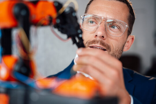 Engineer wearing eyeglasses looking at robotic model