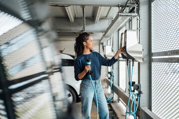 Young businesswoman paying through credit card holding electric plug at parking garage