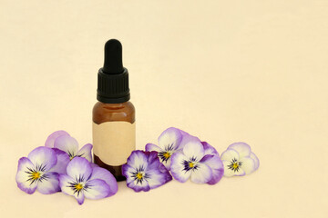 Purple pansy flower essence for alternative herbal medicine with brown bottle on hemp paper. Stress, anxiety, insomnia relieving medicine. Sedative and tranquilizer.
