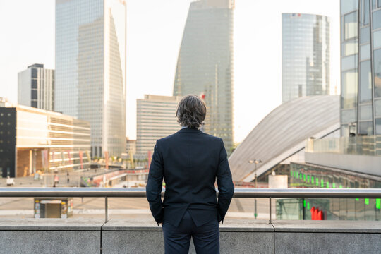 Businessman with hands in pockets standing in front of railing