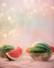 Freshly cut watermelon slices and whole watermelons on a soft blurred foggy background