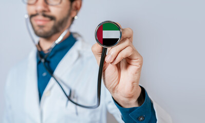 Doctor holding stethoscope with United Arab Emirates flag. United Arab Emirates health and care concept, United Arab Emirates flag on stethoscope