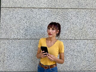 Young woman holding phone, thoughtful and reflective look