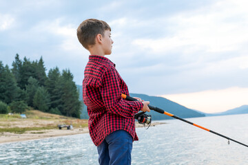 Summer vacation fishing experience kid focusing catching fish mountain lake surrounded forest...