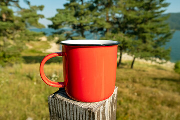 Morning coffee moment near water and trees with classic moka pot and red mug, representing camping,...