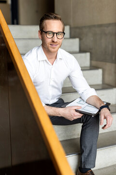 Smiling businessman sitting on staircase in office