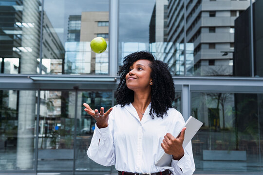 Smiling businesswoman catching apple at office park