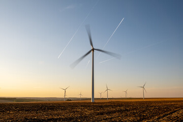 Renewable wind farm in rural region, turbines spinning under clear sky, producing clean energy without emissions, supporting environmental sustainability goals, future of energy captured in scenic