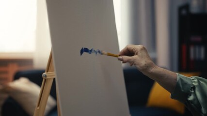 Close-up of woman artist painting a picture on easel stand, art therapy