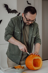 closeup of man carving jack-o-lantern at home,preparing for halloween