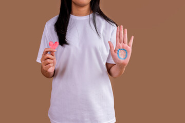 Woman In White Shirt Holding A Red Heart And Showing Palm With Blue Circle, Symbolizing Diabetes Awareness