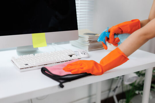 Cleaning lady disinfecting office desk with spray and cloth