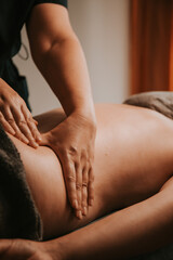 Hands performing massage on back in spa setting