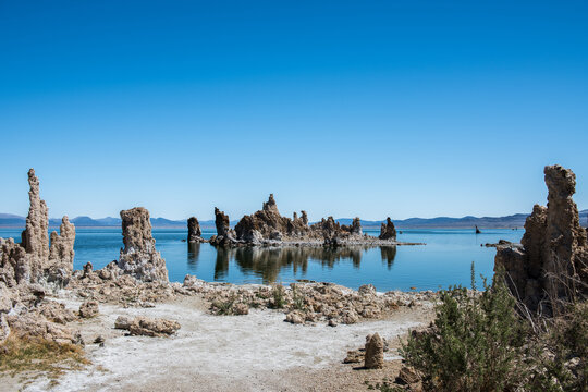 A serene landscape featuring the unique tufa towers of Mono Lake under a clear blue sky, showcasing the natural beauty and geological formations of this California landmark. - Powered by Adobe